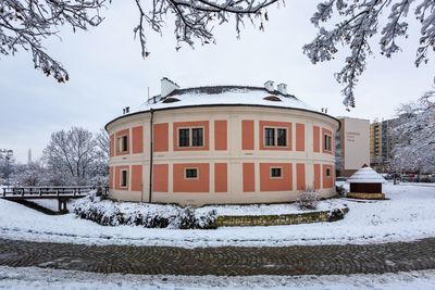 Snow covered field by building against sky