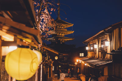 Low angle view of illuminated lanterns hanging outside building against sky at night