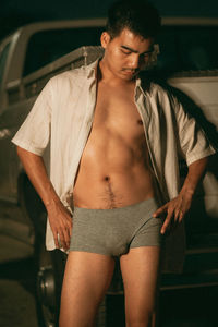 Side view of shirtless man standing in car