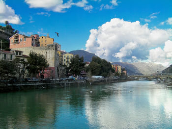 Buildings by lake against sky in city