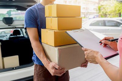 Midsection of man holding cardboard boxes