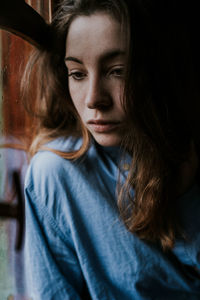 Close-up of thoughtful woman sitting by window at home