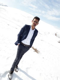 Portrait of young man standing on snow covered field