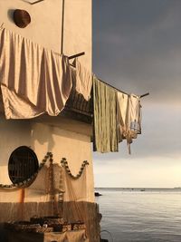 Clothes hanging on roof of building by sea against sky