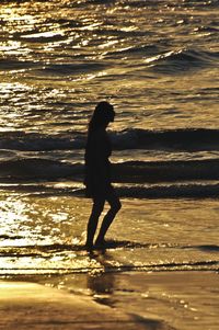 Full length side view of woman on beach during sunset