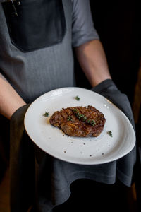 Chef serving rosemary steak on a plate