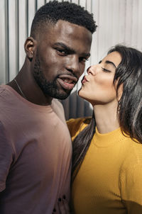 Man kissing woman against wall