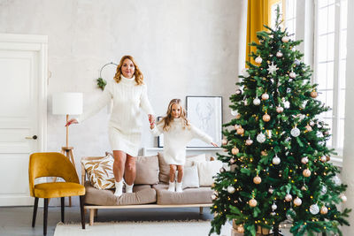 Full length of woman with christmas tree at home