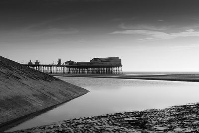 Pier on beach by sea against sky