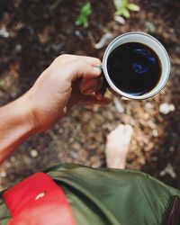 Low section of person holding coffee on field