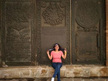 Portrait of smiling mid adult woman sitting against carvings on wall