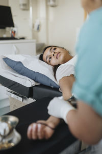 Young woman lying on examination table while surgeon operating in hospital