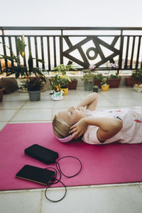 Girl listening to music with headphones lying on terrace
