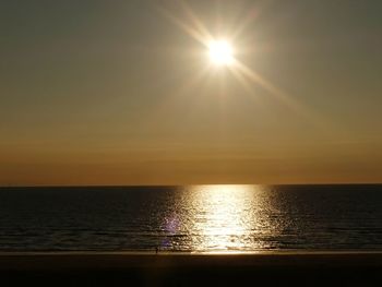 Sunlight streaming through sea against sky during sunset