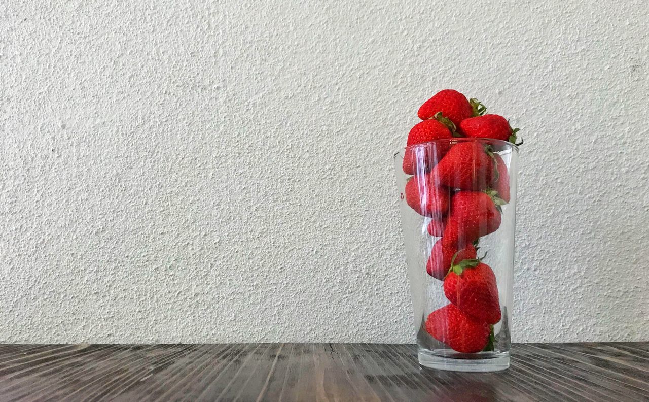 CLOSE-UP OF FRUITS ON TABLE AGAINST WALL