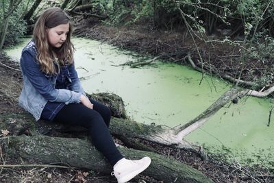 Young woman sitting by lake