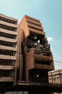 Low angle view of abandoned broken building against sky