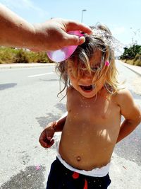 Cropped hand of bursting water bomb on girl head