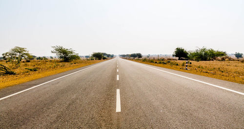 Empty road along landscape and against clear sky