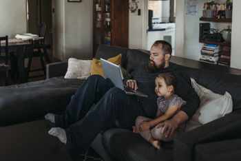 Father working from home with young daughter during isolation