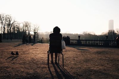 Rear view of man sitting on street against clear sky