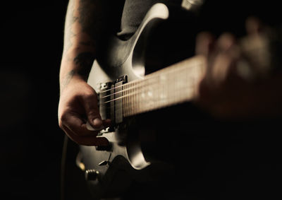 Midsection of man playing guitar