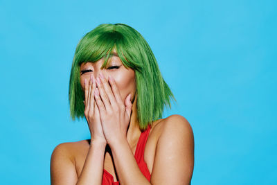 Close-up of young woman against blue background