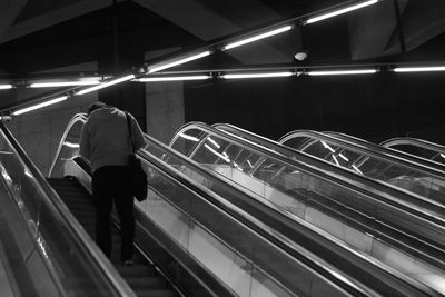 Rear view of man standing on escalator