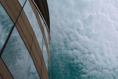 Low angle view of building against sky, sky reflected in windows