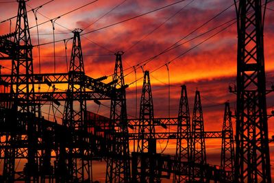 Silhouette electricity pylon against sky during sunset