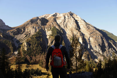 Rear view of man standing on mountain against sky