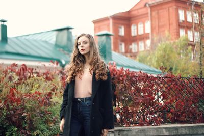 Portrait of young woman standing against plants