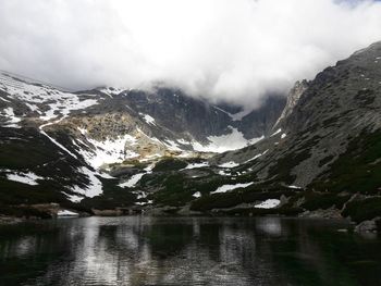 Scenic view of lake by snowcapped mountains against sky