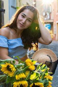 Portrait of beautiful woman holding flower in sunlight