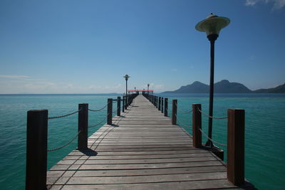 Wooden pier on sea against clear sky