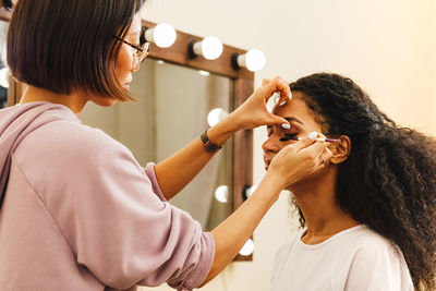 Beautician applying make-up on woman in beauty spa