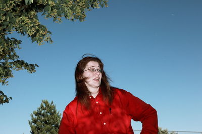 Low angle view of woman standing against blue sky