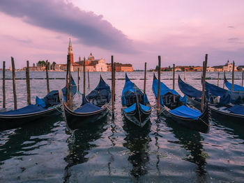 Boats moored in canal at sunset