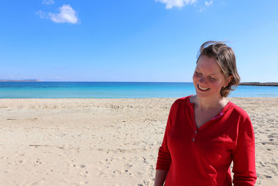 Woman standing at beach against sky