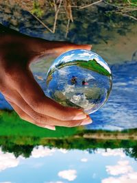 Close-up of hand holding crystal ball with reflection