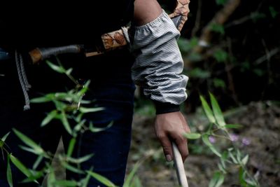 Midsection of man holding stick by plants