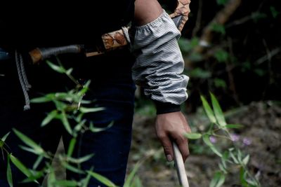 Midsection of man holding stick by plants