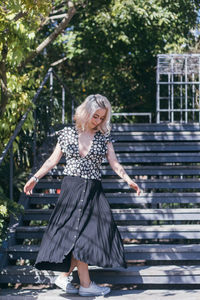 Full length of young woman standing on steps in park