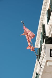 Low angle view of bird flying against building