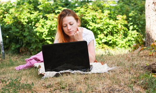Portrait of woman using mobile phone while sitting outdoors