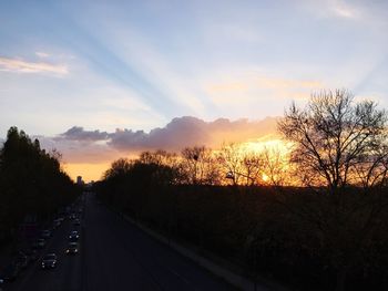 Road amidst trees against sky during sunset