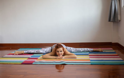 Woman doing yoga on floor at home against wall