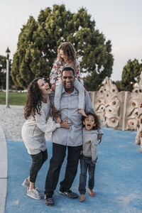 Lifestyle image of beautiful happy family playing in the park at dusk