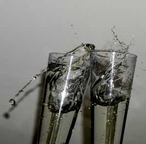 Close-up of water splashing on glass against wall