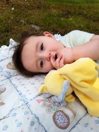 High angle portrait of cute baby boy lying on grassy field at park